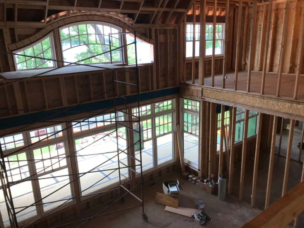 Looking down into the frame of a house under construction. There are many very large windows.