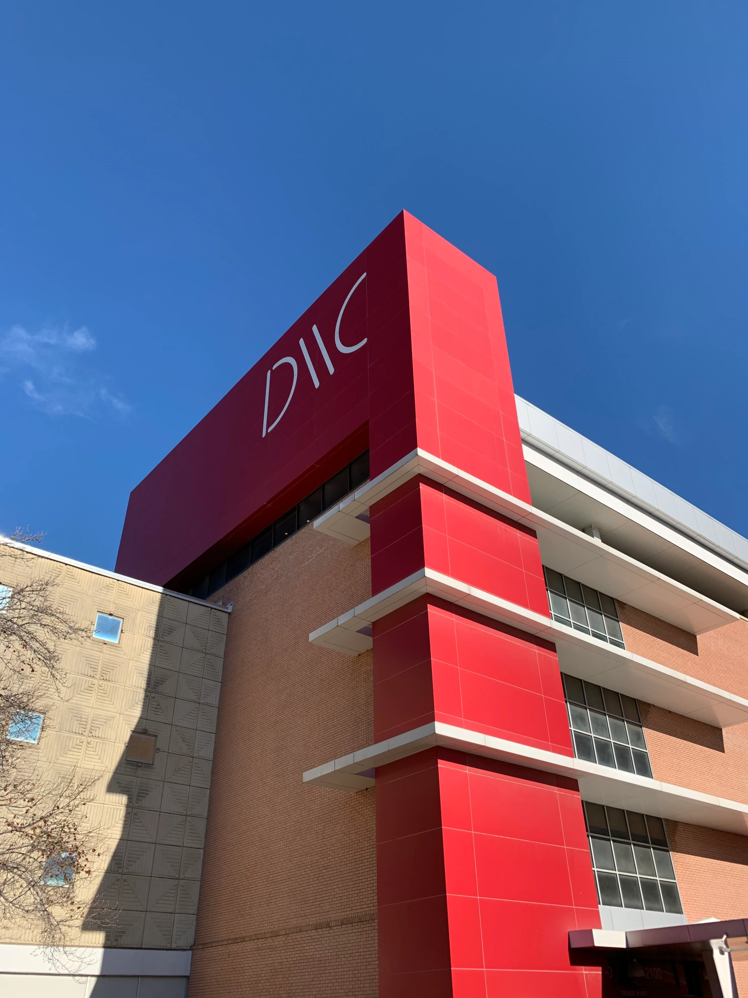 The outside of Dallas Market Center with the logo at the top of a tall red wall