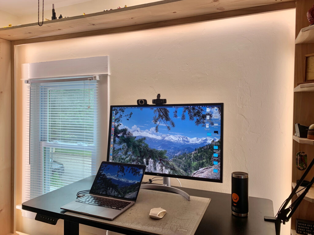 A home office with the wall behind the computer lit up using tape lights around the edges of the wall
