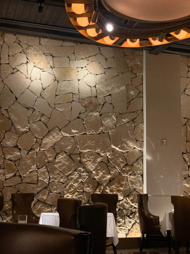 Several restaurant talbles against a stone wall background
