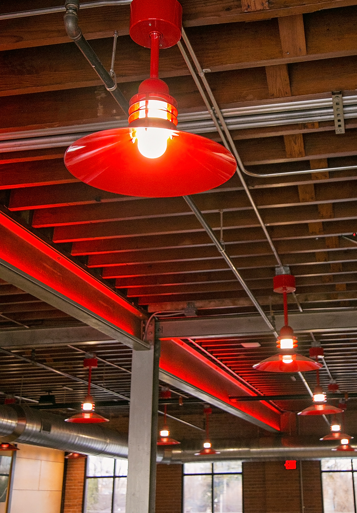 An industrial ceiling with red lamps hanging down at intervals
