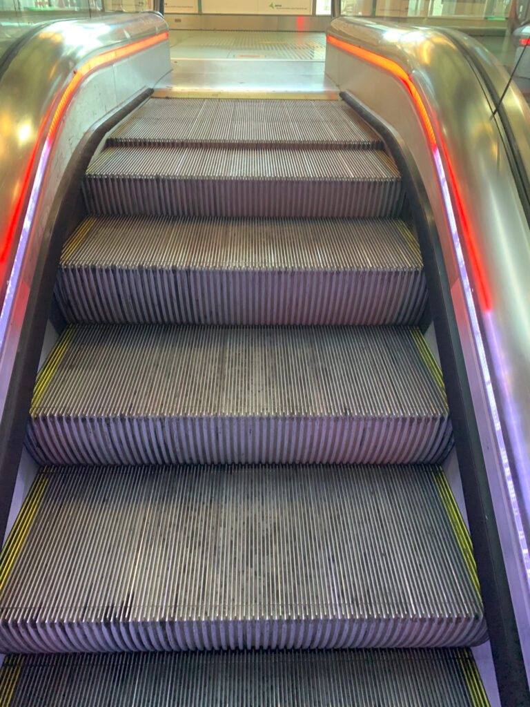 The exit of an up escalator lit up with red light