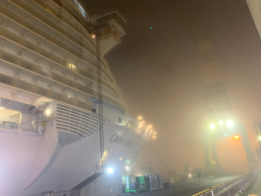 A cruise ship coming to dock in the early morning with spotlight shining on it