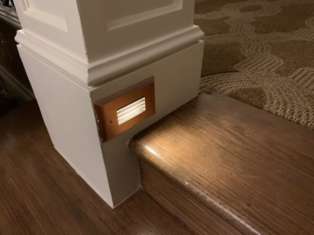 A small light lights up a wooden step indoors.