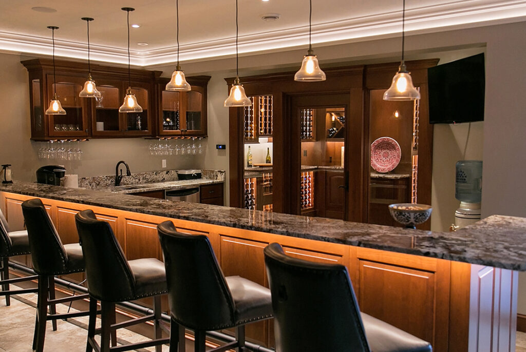 A photograph of a kitchen with a long countertop for diners. All the lights in the kitchen are on